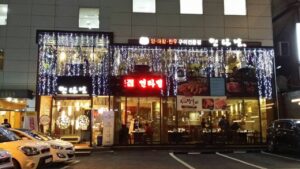 South Korea A restaurant with cars parked in front of it, offering a taste of South Korea.