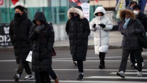South Korea A group of people in winter coats travelling in South Korea, crossing a street.