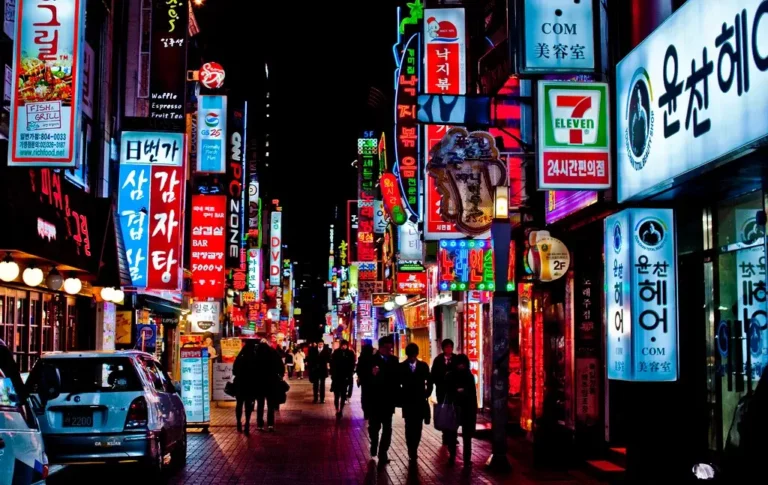 South Korea Travelers exploring South Korea at night, captivated by the vibrant neon signs adorning the streets.